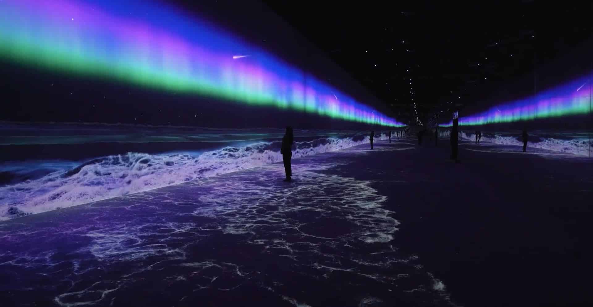 A long hallway glows with digital aurora above and ocean waves below, silhouettes of people add to the surreal atmosphere.