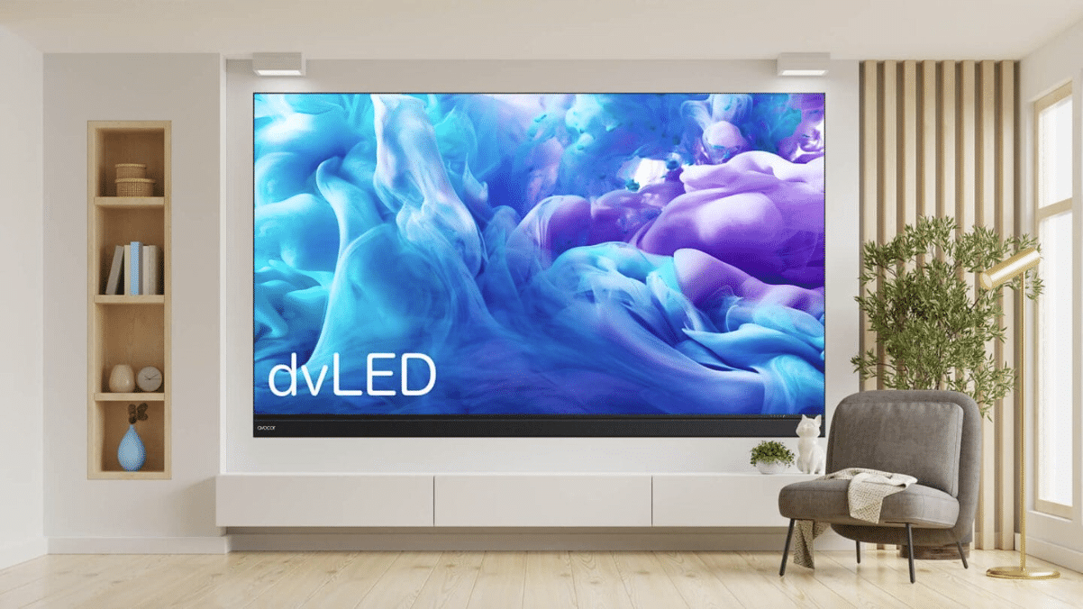 Modern living room: flat-screen TV showing blue/purple art, sleek white cabinet, gray armchair, cushion & plant by large window.